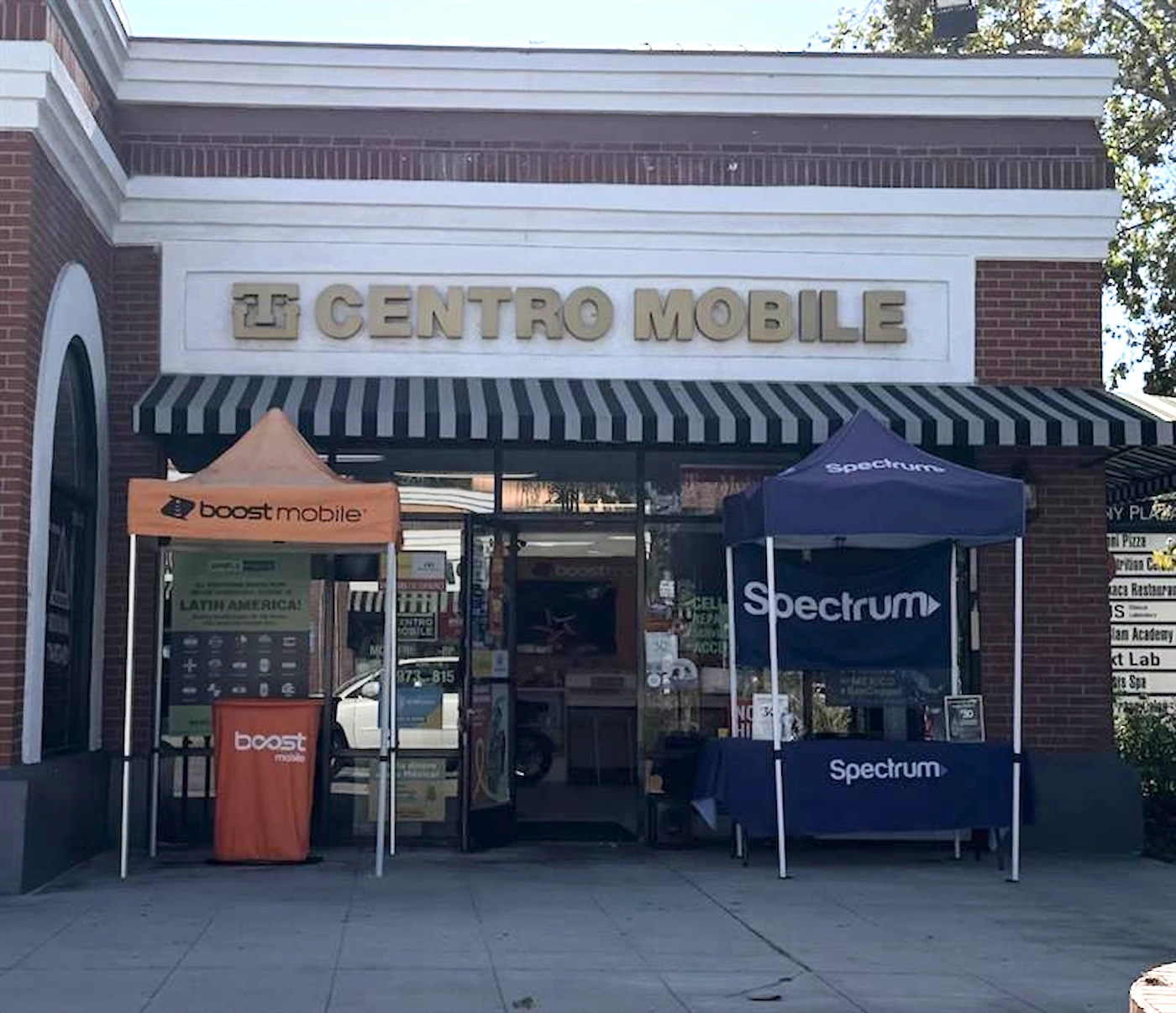 Photo of the front of a prepaid wireless dealer store in California. Boost Mobile and Spectrum tents out in front.