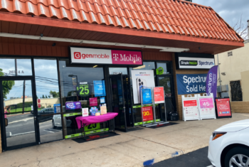 Multi-carrier wireless store displaying Gen Mobile, T-Mobile, Simple Mobile, Ultra Mobile, and Spectrum signage, with phone plan promotions in the windows and outside the entrance.